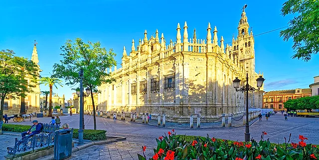 The Gothic exterior of Seville Cathedral with the Giralda behind, in warm light