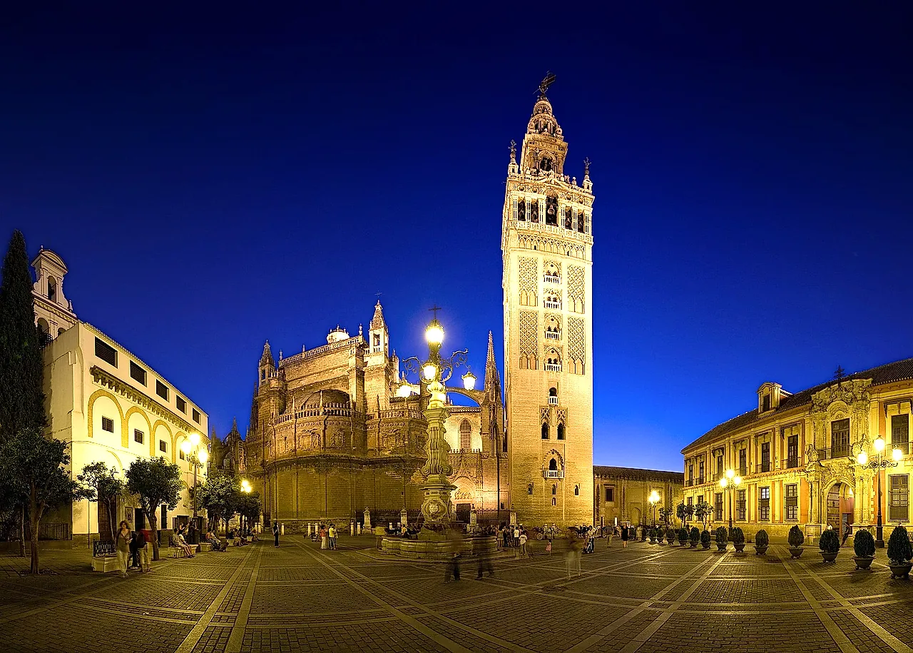 The Giralda and the cathedral lit up at dusk from Plaza Virgen de los Reyes