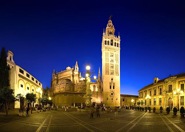 The Giralda and the cathedral lit up at dusk from Plaza Virgen de los Reyes